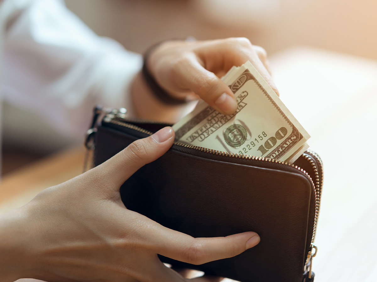 a person pulling large bills out of a wallet