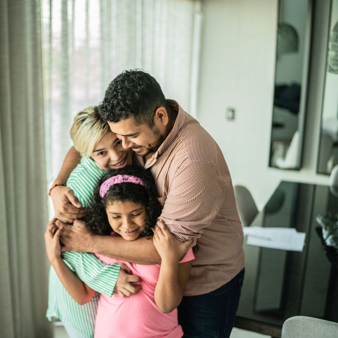 a family hugging in their living room 