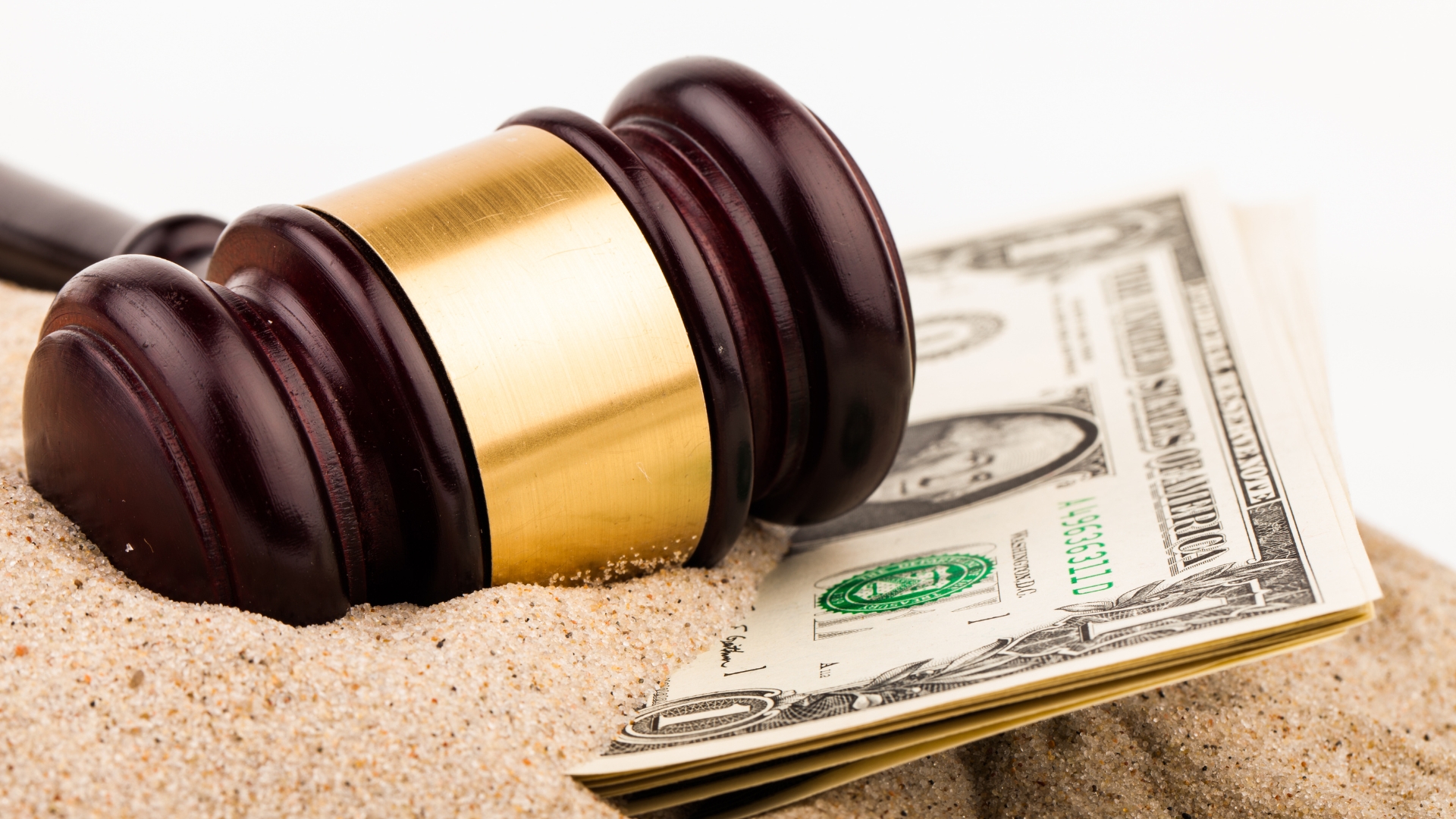 Gavel on top of sand and money