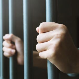 Person holding jail cell bars