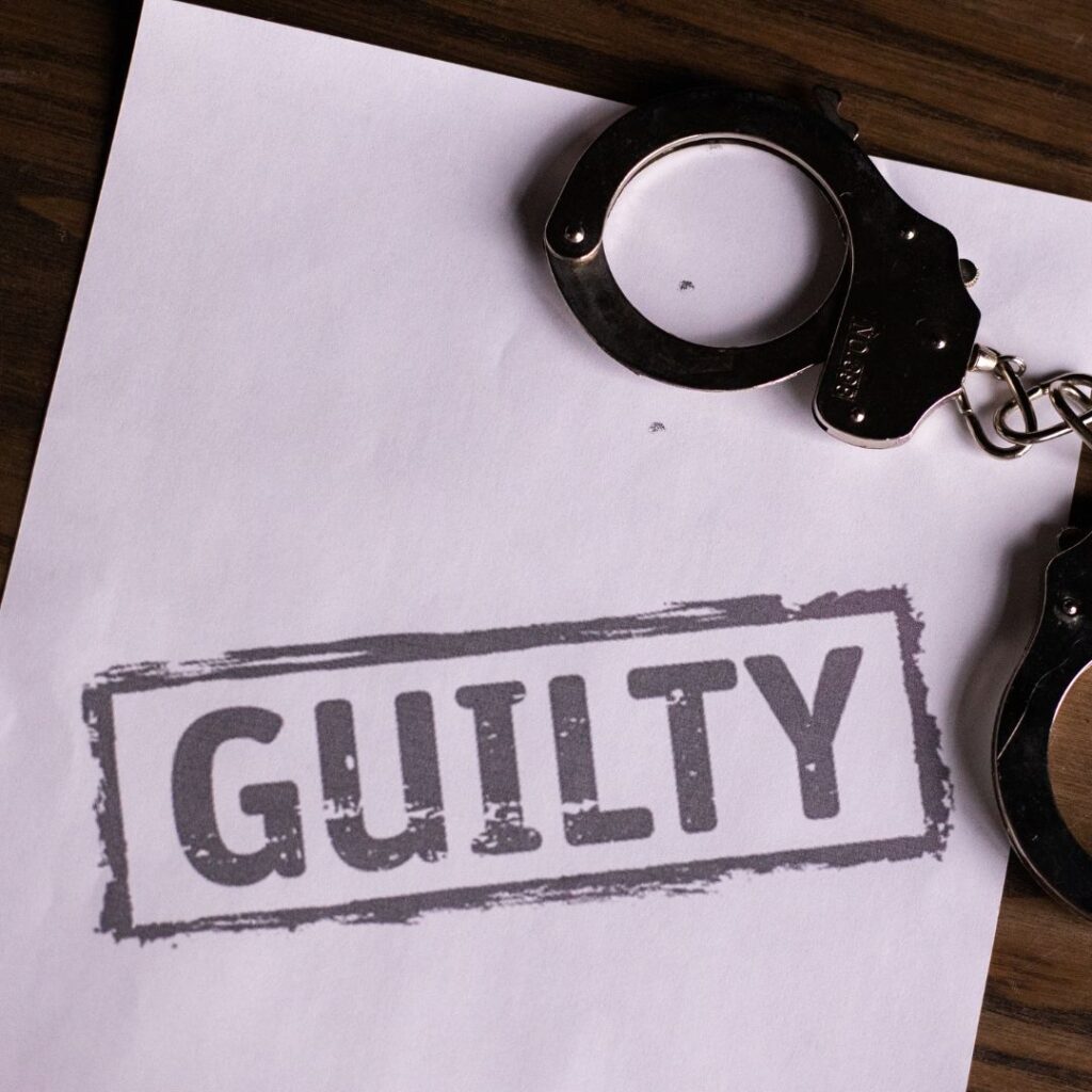 handcuffs on top of paper that says guilty