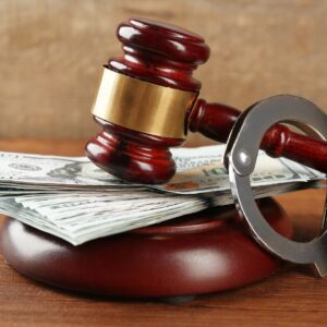 Gavel with handcuffs around it and cash underneath it. 