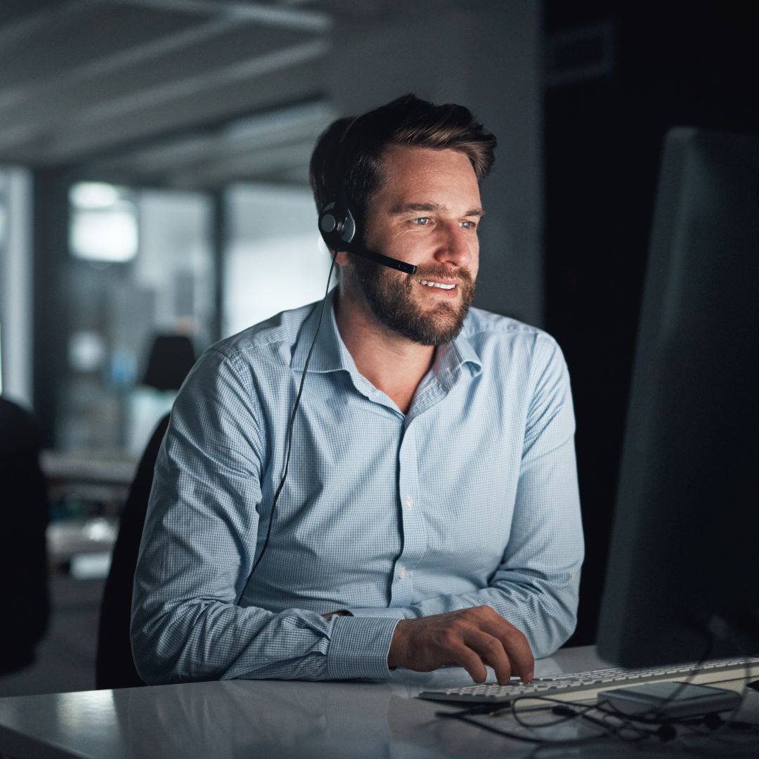man on computer with headset on