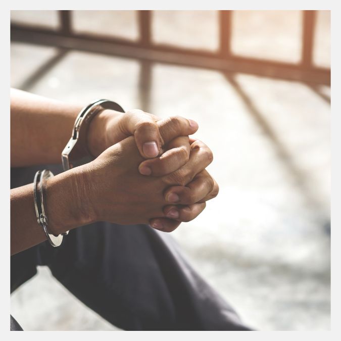 a person in handcuffs sitting in a cell