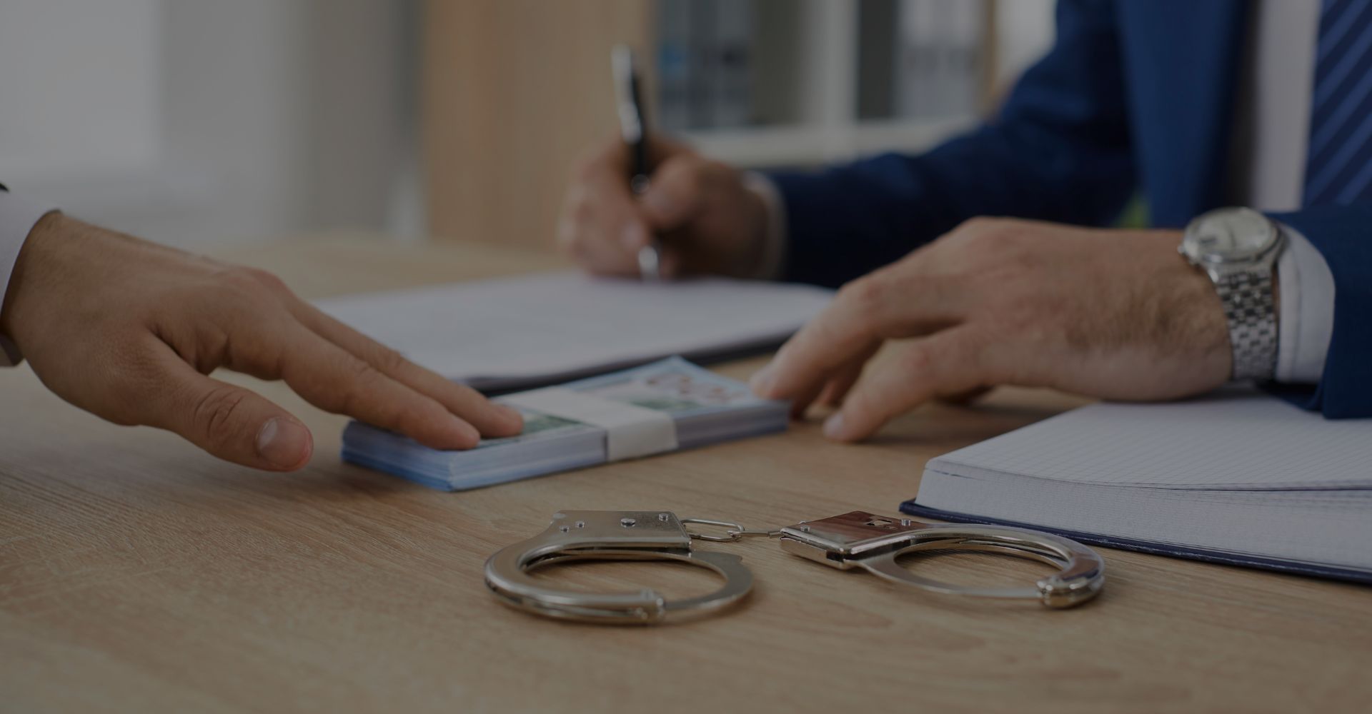 person handing over money with handcuffs on the table
