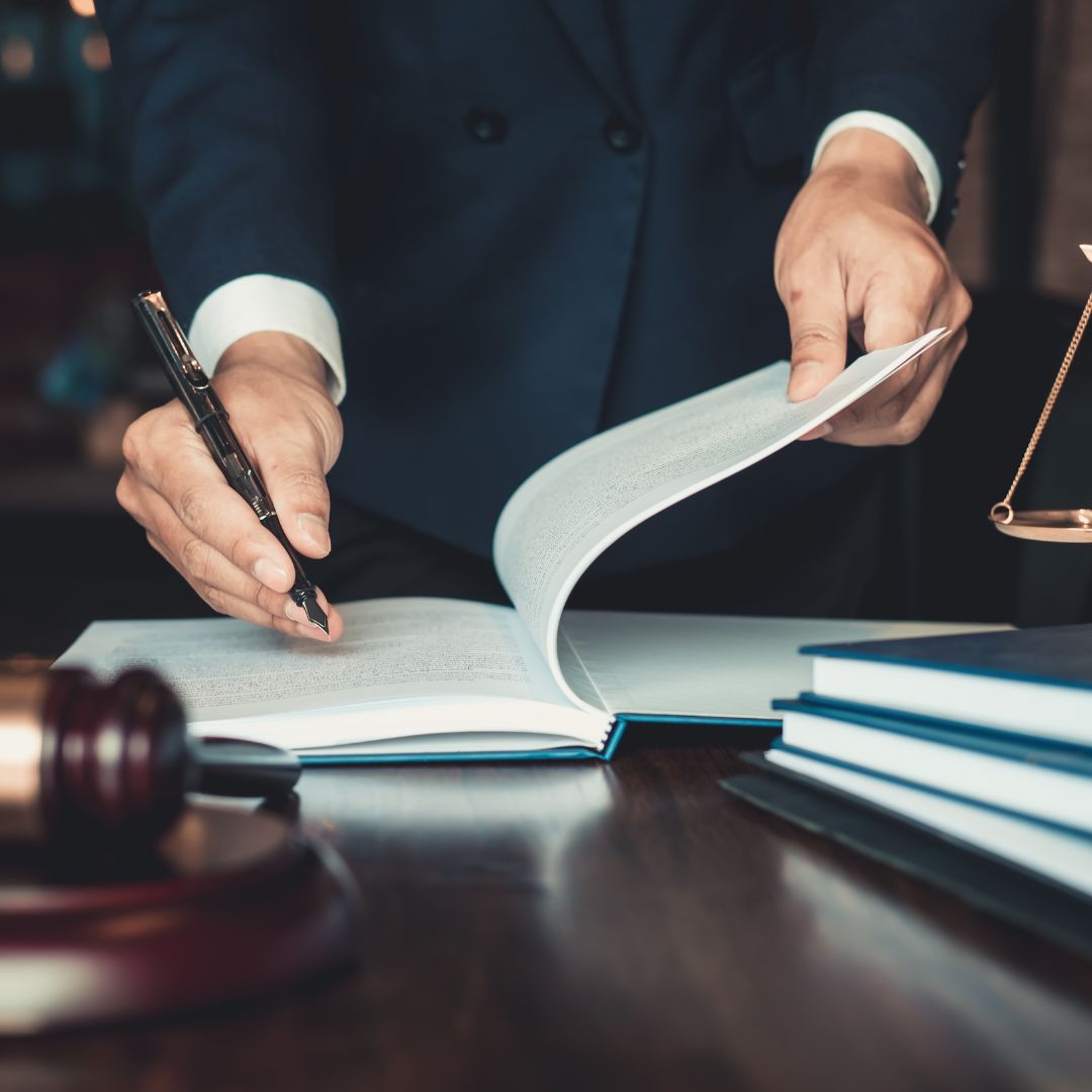 Person in suit signing legal document beside gavel