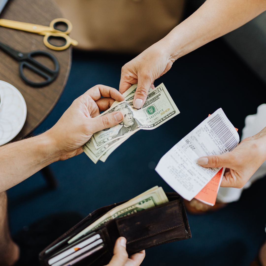 Hands exchanging money and receipt at a table