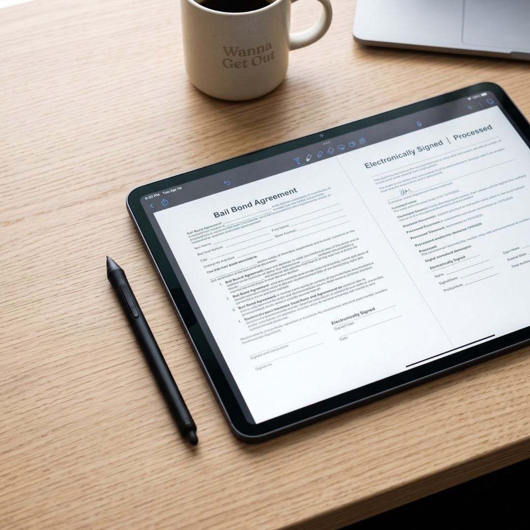 Digital tablet displaying completed electronic documents on a clean desk for remote bail processing.